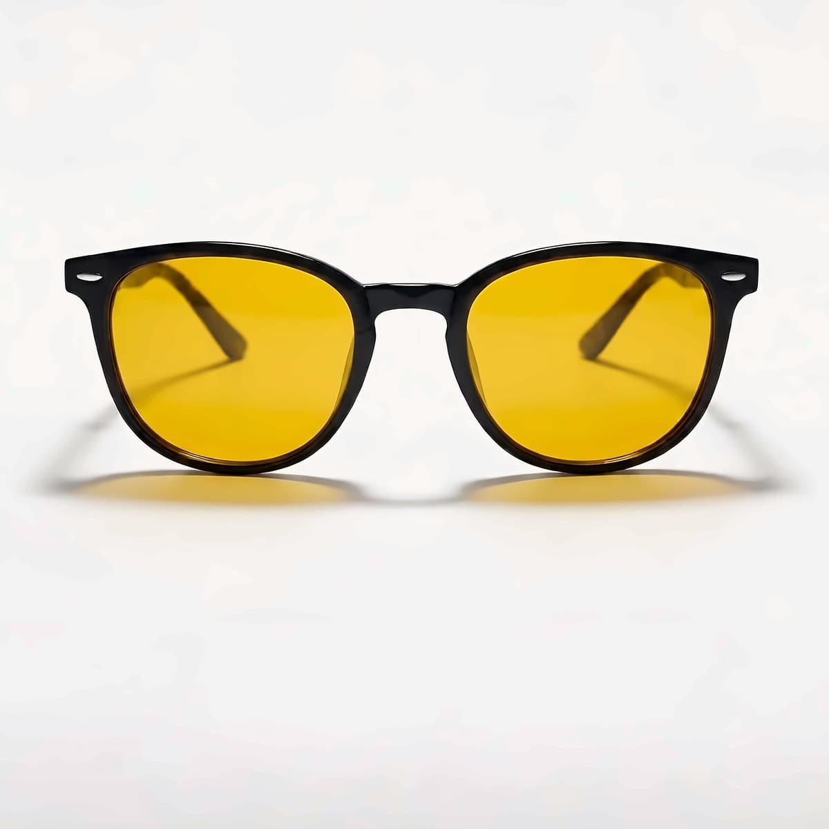 Lunettes Bleuvex Ambris, monture noire et verres jaunes, vues de face sur fond crème