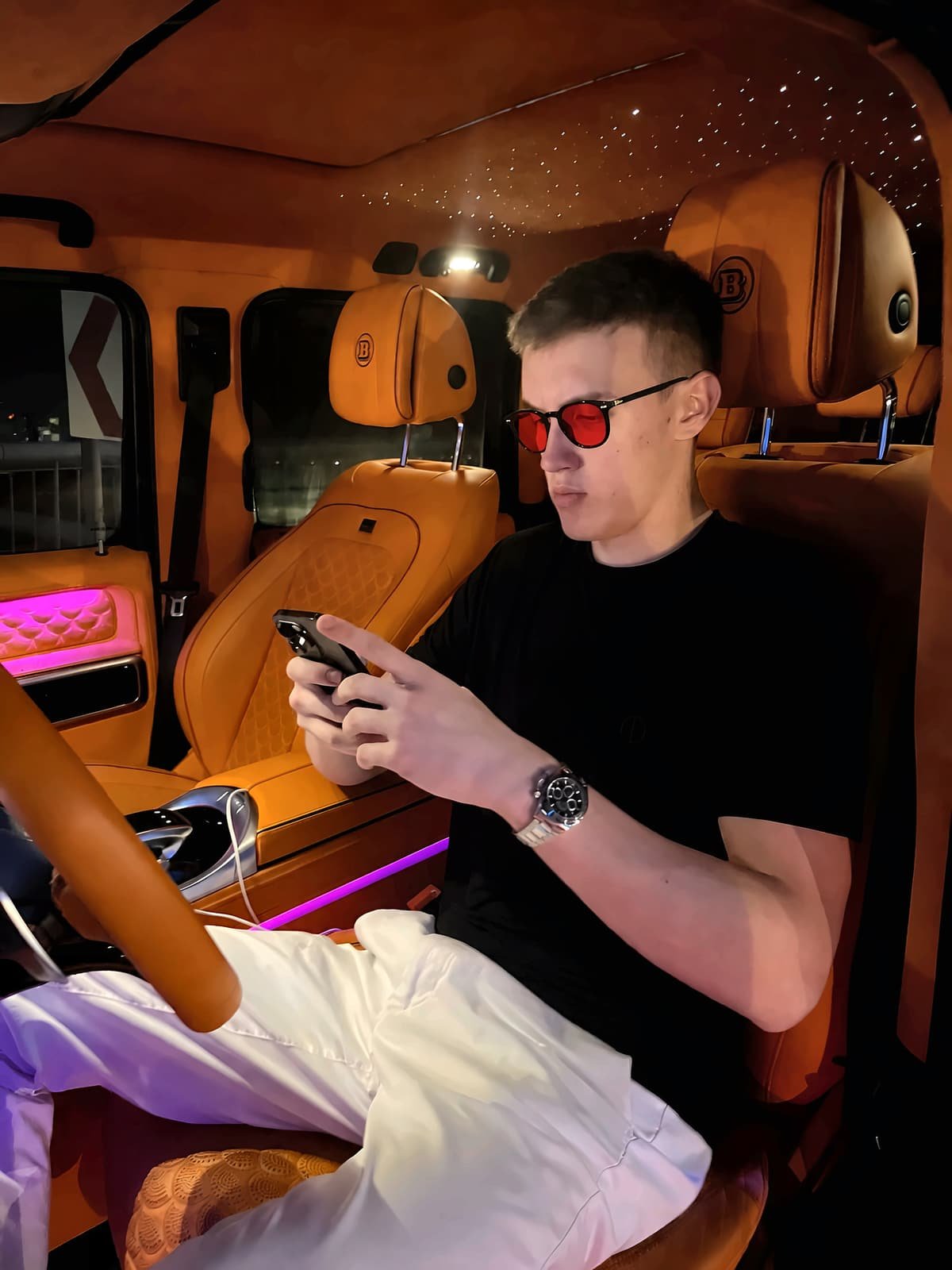 Homme assis dans une voiture à l’arrêt le soir, regardant son téléphone avec des lunettes Bleuvex Noctis